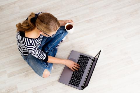Woman on the computer with a cup of coffee in her hand